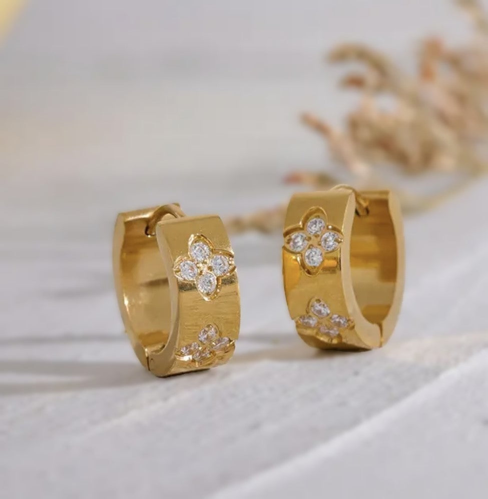 Die funkelnden Mel Ohrringe strahlen zeitlose Eleganz aus. Hergestellt aus Edelstahl und vergoldet mit 18 Karat Gold, sind sie mit glitzernden Zirkoniasteinen besetzt. Ihr vielseitiges Design macht sie zu einem perfekten Accessoire für jeden Anlass.